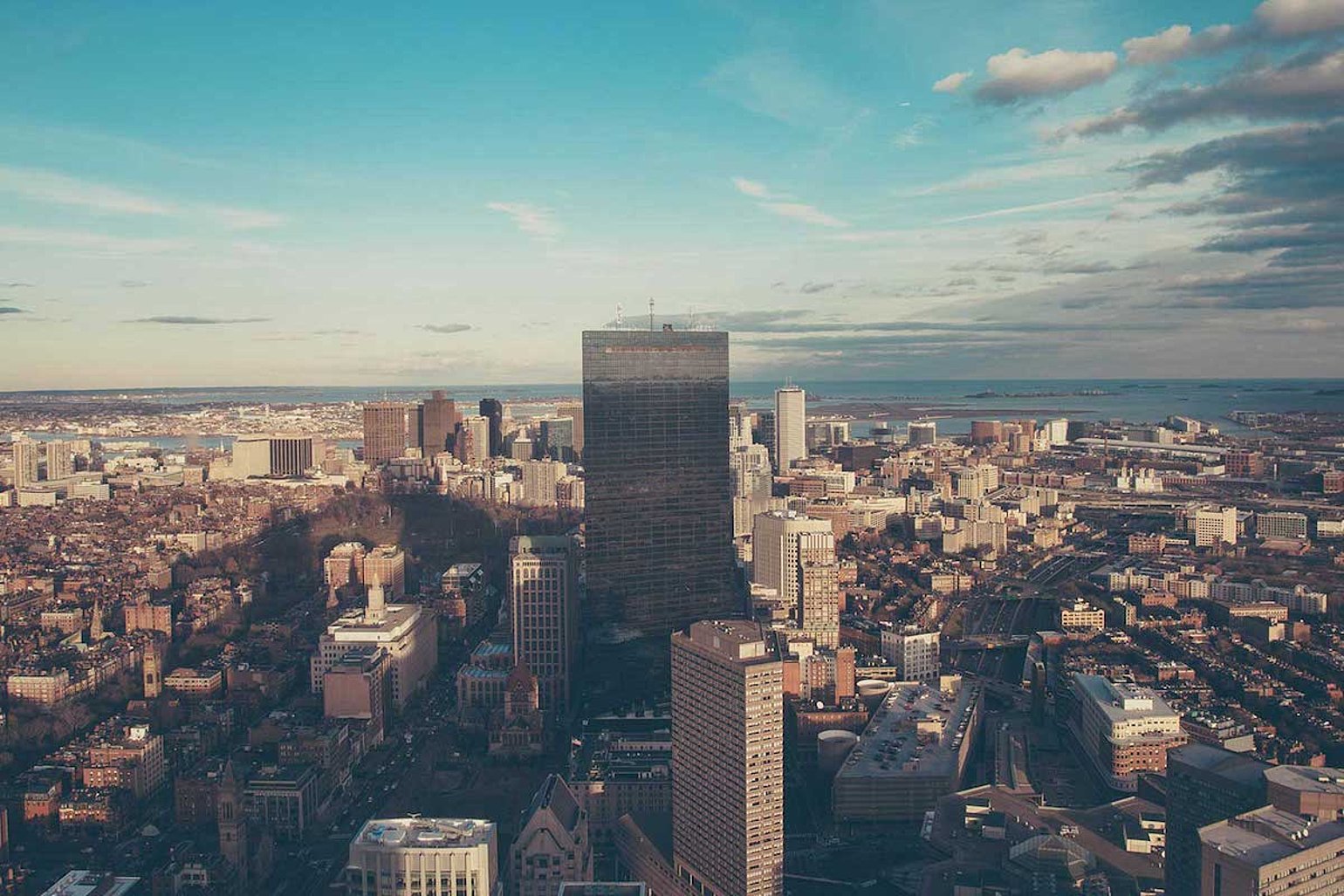 Luftaufnahme einer grossen Stadt mit hohen Gebaeuden und Wasser im Hintergrund